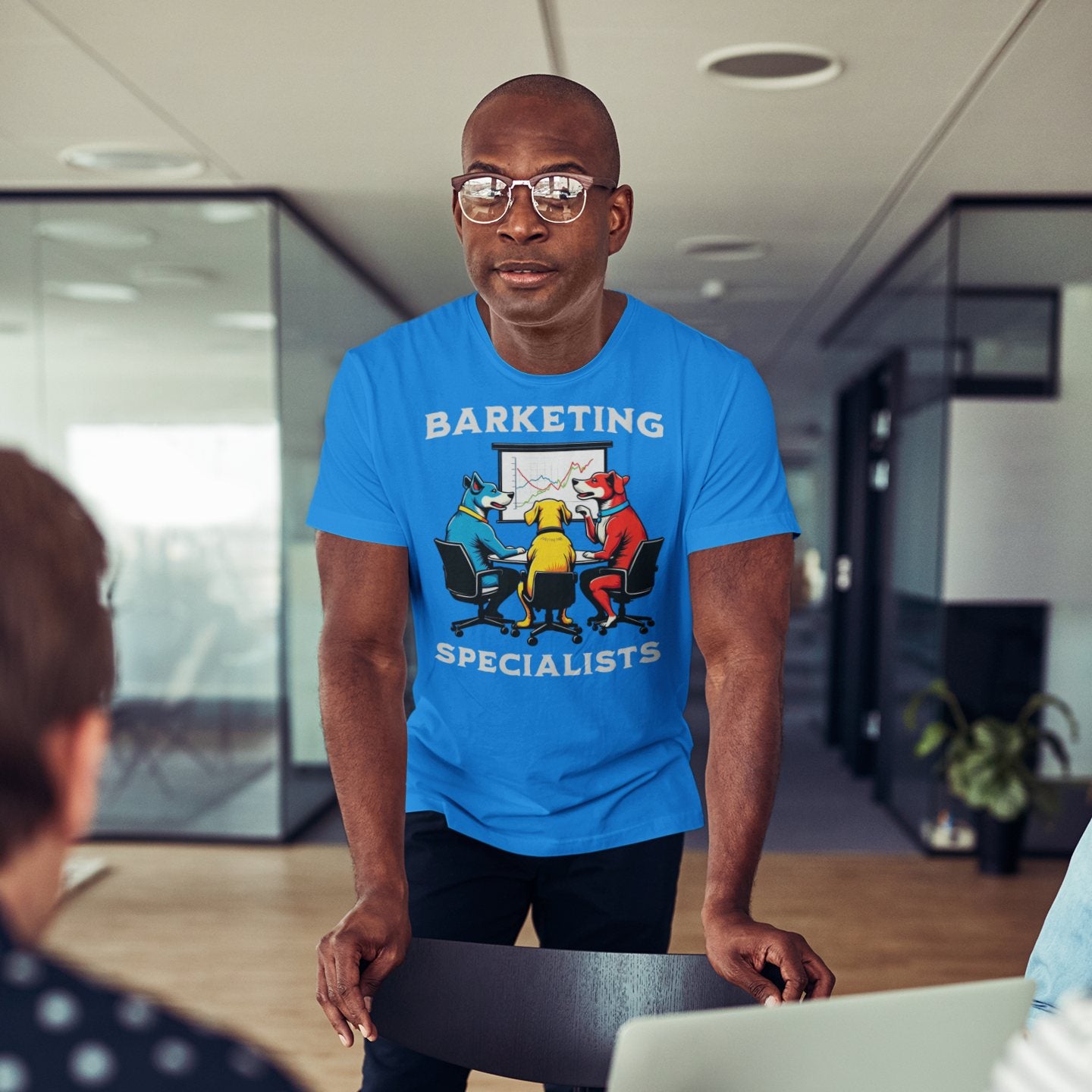 Man wearing Barketing Specialists t-shirt in a meeting room, smiling in blue shirt with funny dog marketing graphic