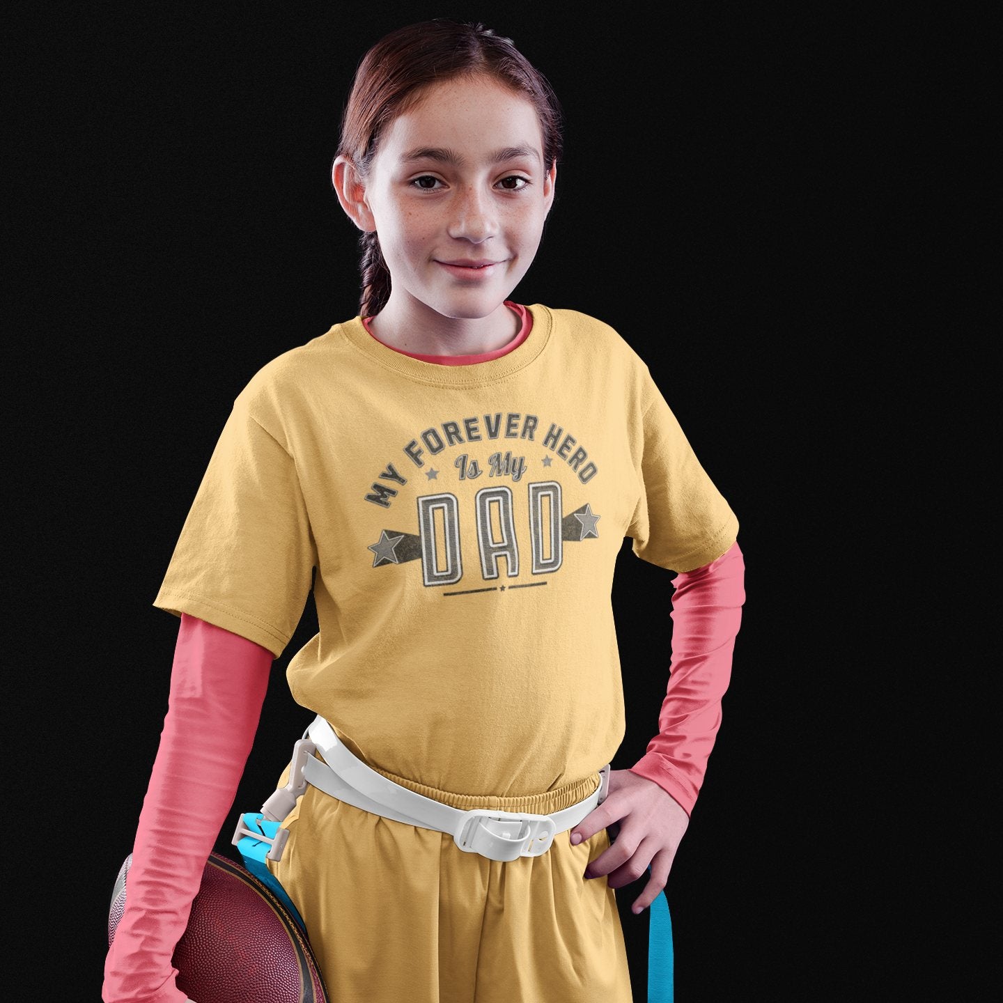 Young girl posing confidently in yellow tribute shirt reading “My Forever Hero Is My Dad”