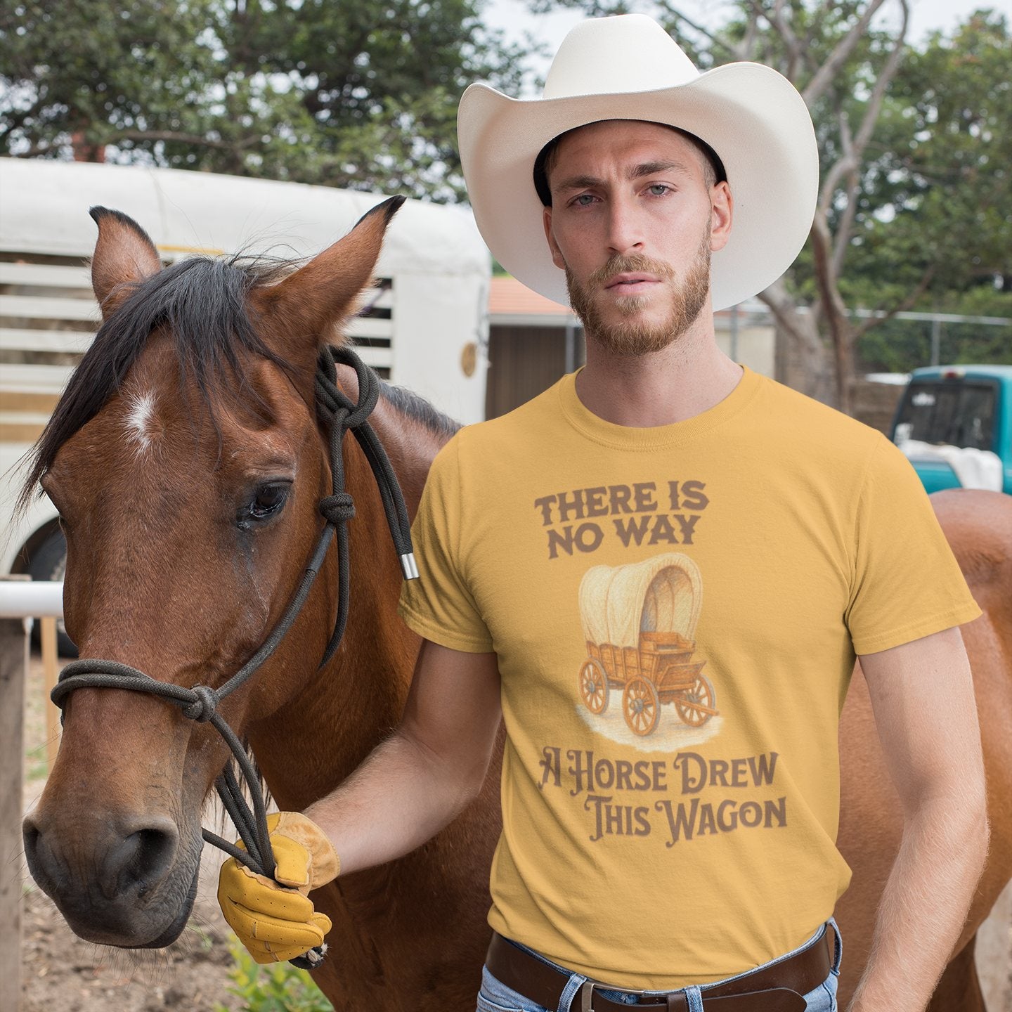 Cowboy standing with horse, wearing yellow funny shirt that says “There’s No Way a Horse Drew This Wagon”