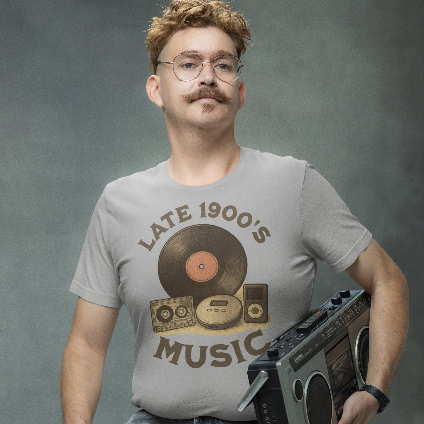 Man wearing retro “Late 1900s Music” t-shirt holding a cassette player, smiling ironically