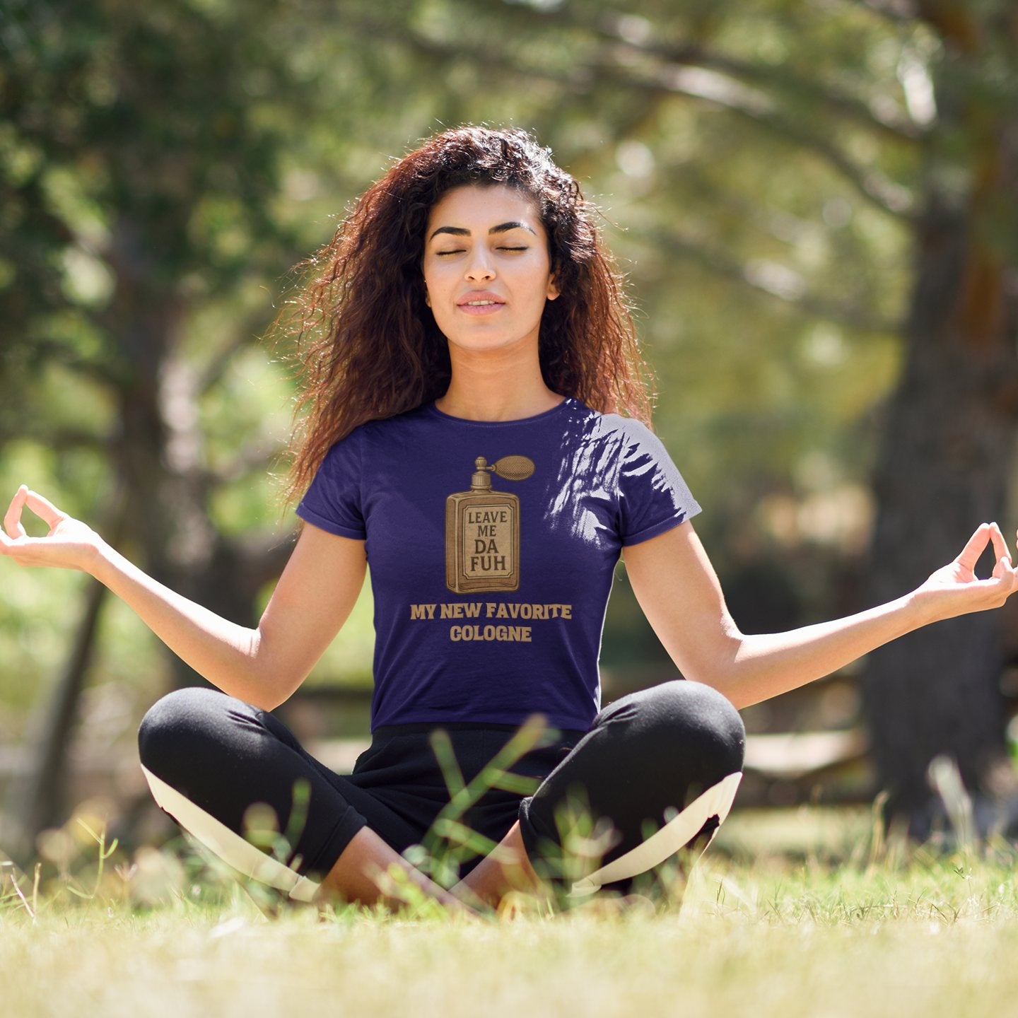 Woman meditating outdoors while wearing purple “Leave Me Da Fuh” t-shirt with sarcastic cologne bottle design