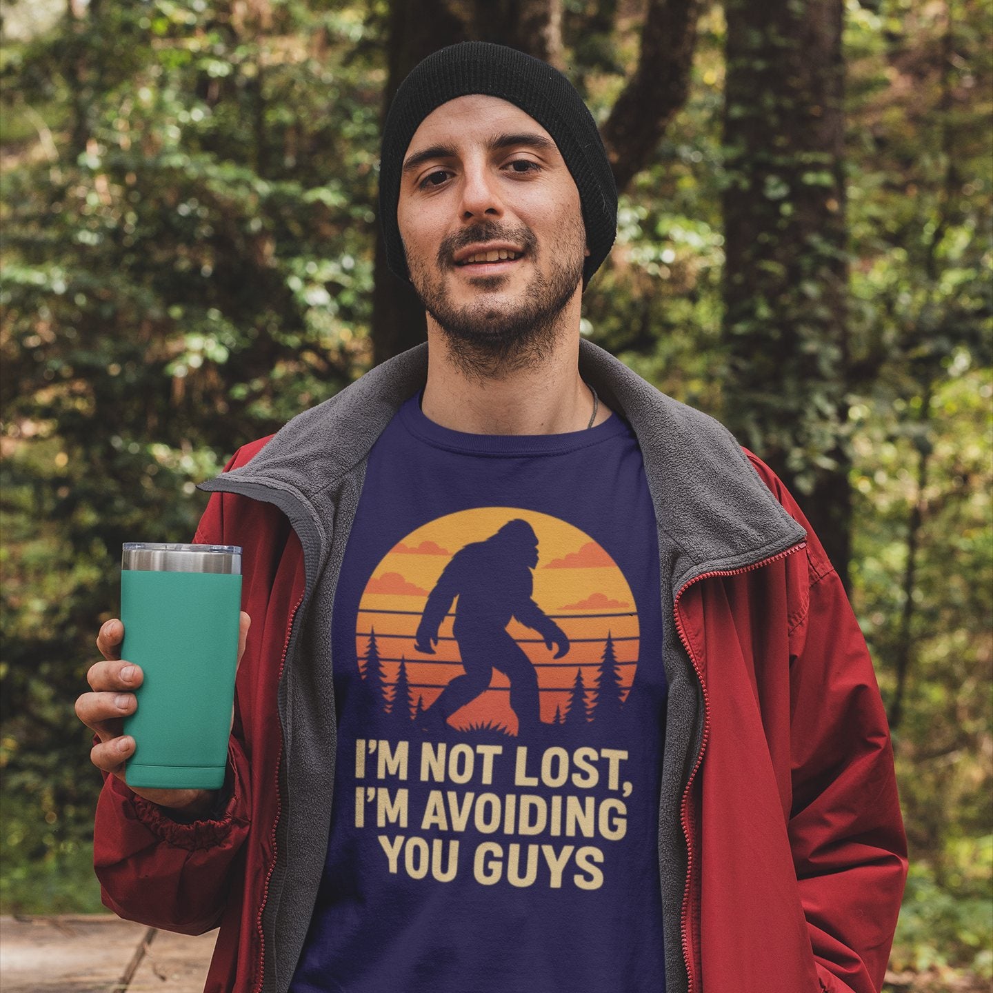 Model wearing funny bigfoot “I’m avoiding you” shirt in outdoor wooded setting