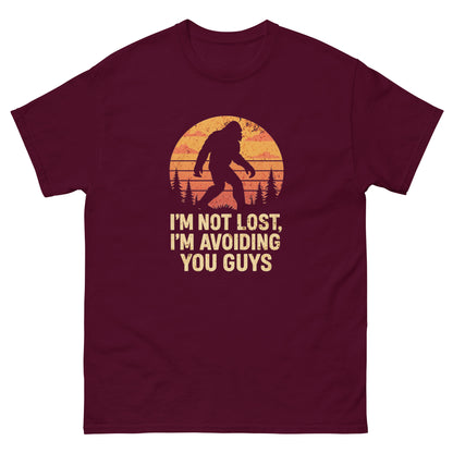 Maroon funny bigfoot t-shirt with “I’m not lost, I’m avoiding you guys” forest sunset design