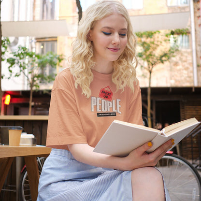 Woman wearing "Shut Up People, I'm Reading a Book" funny t-shirt, holding a book