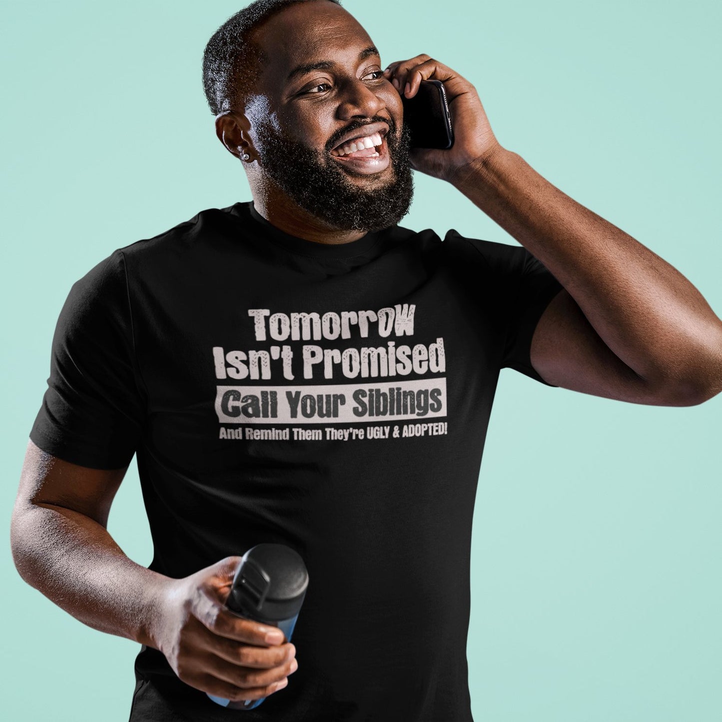 Man laughing while wearing black sibling prank shirt with “Tomorrow Isn’t Promised” funny quote